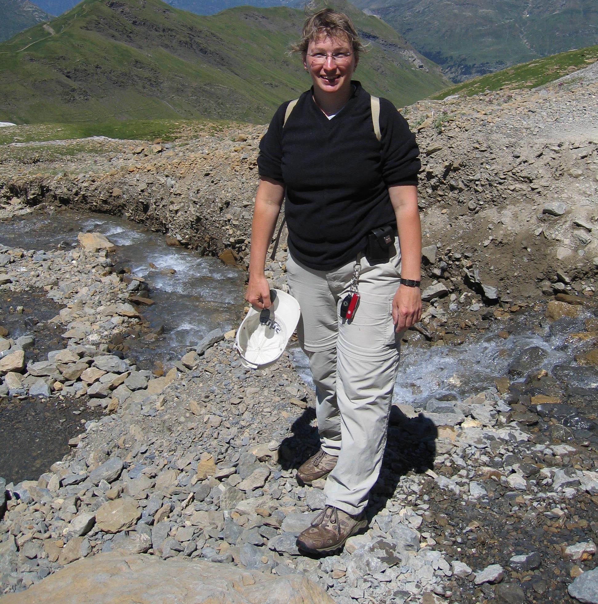 Amy standing beside a mountain stream on a hiking trip