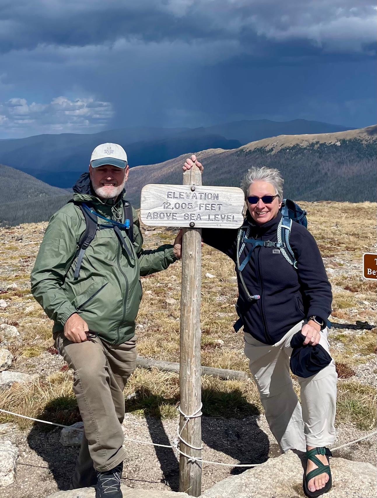 Amy and her husband Randy at a mountain summit, elevation 12,005 feet, with storm clouds in the distance